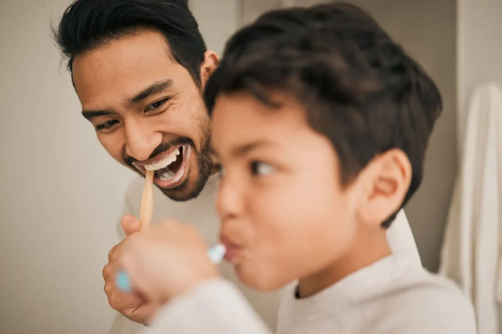 parent brushing teeth with his children